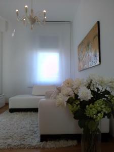una sala de estar con un sofá blanco y flores en Appartamento in Villa en Pesaro