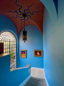 un couloir avec des murs bleus et un plafond avec un lustre dans l'établissement PALAZZO FIACCADORI - Historical Palace, à Reggio de Calabre