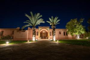 un bâtiment avec des palmiers et des lumières la nuit dans l'établissement L’oasis de kima, à Taroudant