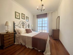 a bedroom with a bed and a dresser and a window at Piso Os Pazos in Cambados