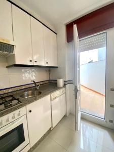 a kitchen with white cabinets and a sink and a window at Piso Os Pazos in Cambados +9 photos