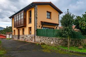 a yellow house with a stone wall at Casa Sabina, Zona de playa y montaña in Llanes