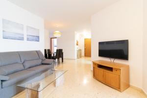 ein Wohnzimmer mit einem Sofa und einem Flachbild-TV in der Unterkunft Global Properties, Increible apartamento en la playa, Canet d'en Berenguer in Canet d'en Berenguer