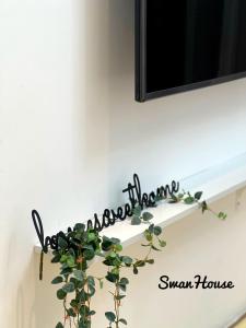 a black metal sign hanging on a white wall with a plant at Premium Swanhouse no.SiX with 3bedrooms Condo in Sibu