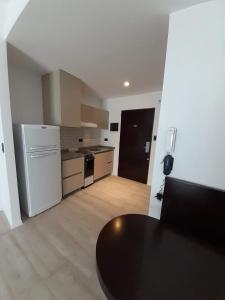 a kitchen with a black table and a white refrigerator at Carpinchos De Otamendi in Campana