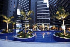 una piscina con palmeras frente a edificios altos en Apartamento Beira Mar by WL Temporada, en Fortaleza