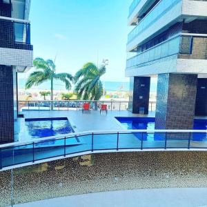 un balcón de un edificio con piscina y palmeras en Apartamento Beira Mar by WL Temporada, en Fortaleza