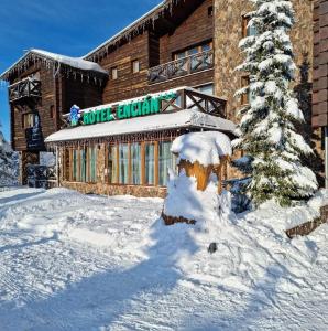 un edificio con un árbol cubierto de nieve delante de él en Horsky Hotel Encian Donovaly en Donovaly