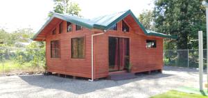 una pequeña casa de madera con techo verde en Cabaña Tio King, en Uvita