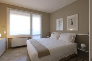 sypialnia z dużym białym łóżkiem i oknem w obiekcie Contempora Apartments - Elvezia 8 - E51 w Mediolanie