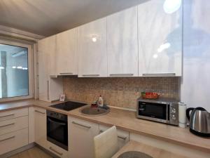 una cucina con mobili bianchi, un lavello e un microonde di Contemporary central apartment in Cluj Napoca a Cluj-Napoca