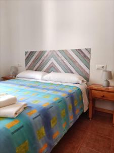 Un dormitorio con una cama con un edredón colorido. en La Rueda Apartamentos Rurales, en Chulilla