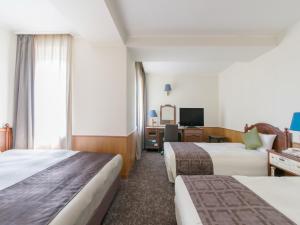 Premier Hotel -CABIN- Obihiro في أوبيهيرو: غرفة فندقية بسريرين ومكتب