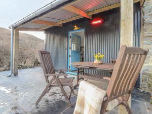 two chairs and a wooden table on a patio at Dolwylan Barn in Llandysul