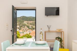een witte eetkamer met een tafel en een raam bij Antheon apartments in Vathi