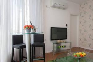 een woonkamer met een tafel en twee stoelen en een televisie bij Yellow Gordon Beach Apartment in Tel Aviv