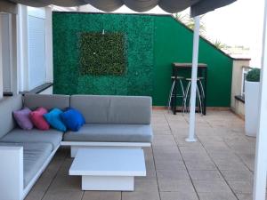a couch on a patio with a green wall at Ático de lujo con vistas al mar in Sant Carles de la Ràpita
