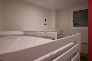 a white bedroom with a large bed in it at Hostel Trovadores in Burgos
