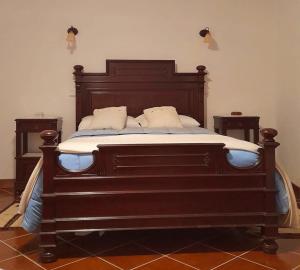 a large wooden bed in a room with two tables at Casa Do Seminario in Gralhas
