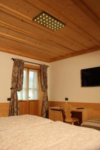 a bedroom with a bed and a flat screen tv at Jägerhaus Agriturismo in Cortina dʼAmpezzo