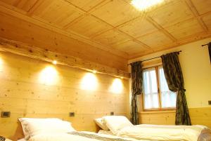 two beds in a room with a wooden wall at Jägerhaus Agriturismo in Cortina dʼAmpezzo
