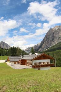 a house in a field with mountains in the background at Jägerhaus Agriturismo in Cortina dʼAmpezzo