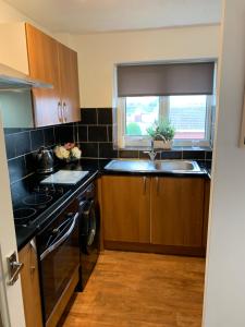 a kitchen with a sink and a stove and a window at Sunny rhyl apartment in Rhyl