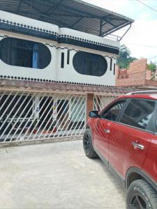 ein rotes Auto, das vor einem Haus parkt in der Unterkunft HOSPEDAJE EL CANTARO in Tingo María