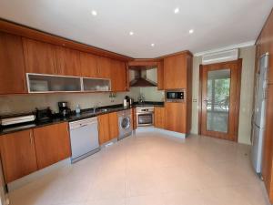 a large kitchen with wooden cabinets and appliances at Apartamento em Tavira by Homekeys in Tavira