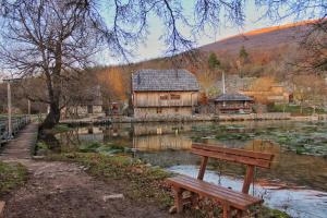 a bench sitting in front of a lake with a building at Honey house Lika in Gospić