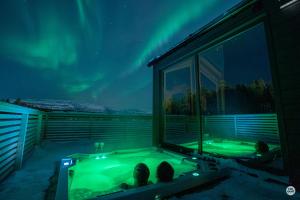 a hot tub in a room with a view of the northern lights at Flatmoen Natur Lodge in Alta