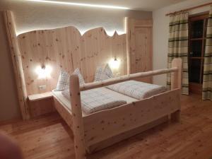 ein Holzbett mit einem Kopfteil aus Holz in einem Zimmer in der Unterkunft Schweiggerhof in Villanders