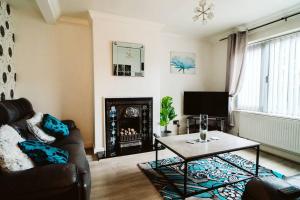 a living room with a couch and a table and a fireplace at Turves Place, 3 Bedroom property/near MCR Airport in Cheadle Hulme