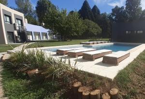 a swimming pool with lounges and lounge chairs next to a house at Carpinchos De Otamendi in Campana