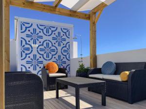 a patio with chairs and tables and a blue wall at My Residence Alvor in Alvor