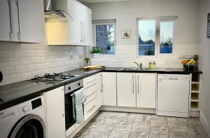 een keuken met witte kasten en een fornuis met oven bij Three Bedroom City Home with Garden in Southampton