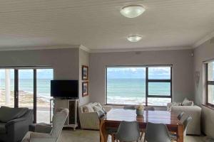a living room with a table and chairs and the ocean at Bakgat Stay - Seafront 7-sleeper holiday home in Struisbaai