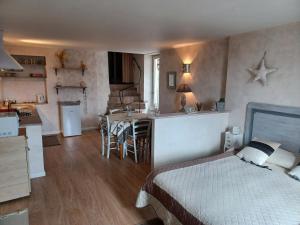 a bedroom with a bed and a kitchen with a table at Le studio côté chapelle in Coursegoules