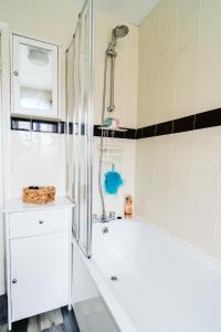 uma casa de banho branca com uma banheira e um chuveiro em Turves Place, 3 Bedroom property/near MCR Airport em Cheadle Hulme