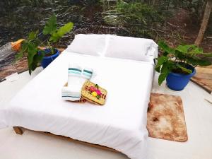 una cama blanca con una servilleta con plantas en Glamping Amazonas, en Leticia