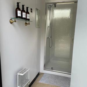a bathroom with a shower with bottles of wine on a shelf at Trethowels Hidden Huts in St Austell