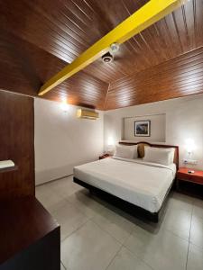1 dormitorio con 1 cama grande y techo de madera en Abad Harmonia Ayurvedic Beach Resort, en Kovalam