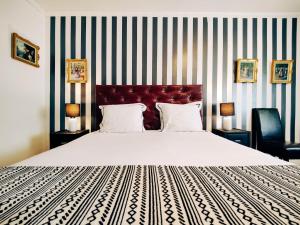 ein Schlafzimmer mit einem großen Bett und einer gestreiften Wand in der Unterkunft Boutique Hotel Joli Bois in De Haan