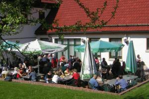 eine Gruppe von Personen, die an Tischen mit Sonnenschirmen sitzen in der Unterkunft Hotel Brückenmühle in Meiningen