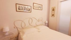 a white bedroom with a white bed and two pictures on the wall at Relais Pacinotti Rooms in Pisa