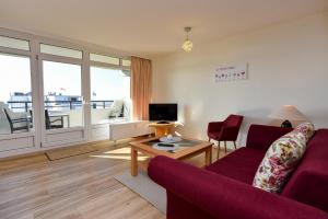 a living room with a red couch and a table at Haus "Panorama" Appartement PAN086 in Duhnen