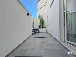a walkway between two white buildings with a potted plant at La Maison Fois - Appartamento Quartucciu in Quartucciu