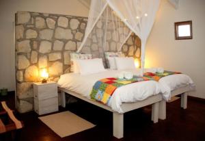 a bedroom with a bed with a stone wall at Gondwana Kalahari Farmhouse in Stampriet