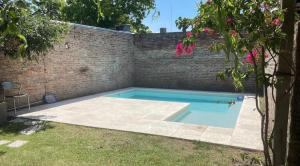 a swimming pool in a backyard with a brick wall at Lo de Hugo in Muñiz