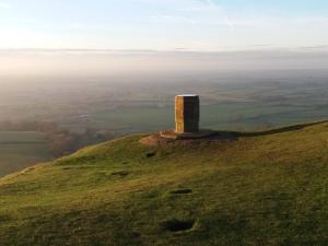 una torre di pietra in cima a una collina erbosa di Cotswold Aparthotel a Stroud